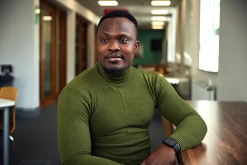 Student Chidiebere Ejiogu sits at a table in Treforest campus's Postgraduate Centre