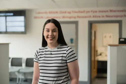 A female psychology students stands confidently in front of the camera whilst smiling
