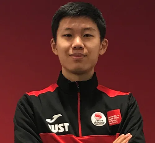 MSc Sport student Siteng Wang smiles at the camera with their arms crossed in front of a red backdrop