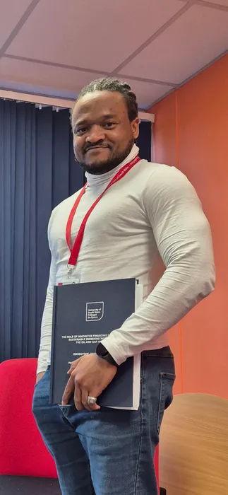 Omoboyede Alalabiaye standing wearing USW lanyard and holding thesis