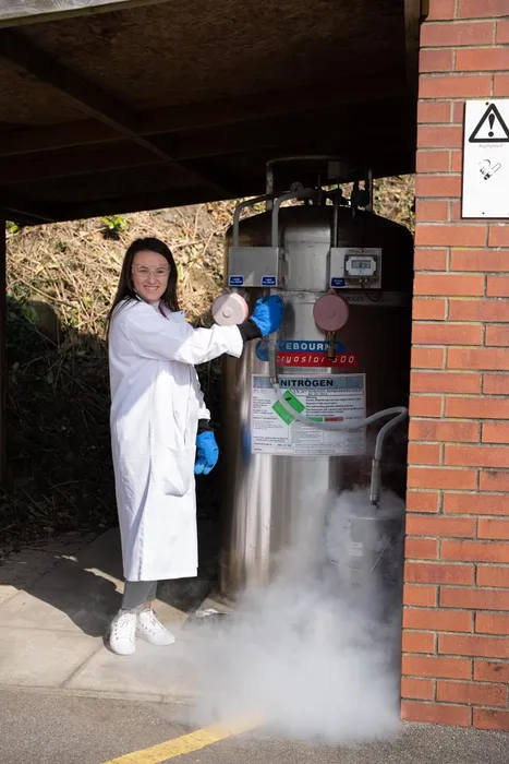PhD student Shannan taking part in a science experiment, wearing a lab coat and safety goggles