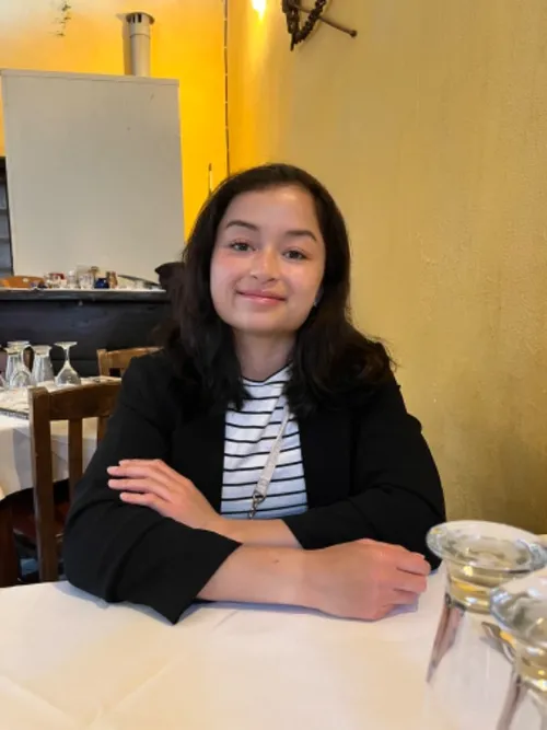 A photograph of Norwegian student, Emma, smiling at the camera in a cafe