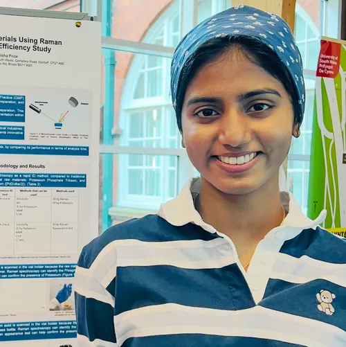 Student Senushi Jayasinghe smiles at the camera while stood in front of a USW biotech poster