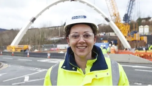 Close up image of Engineering student, Angharad, smiling at camera in front of construction project