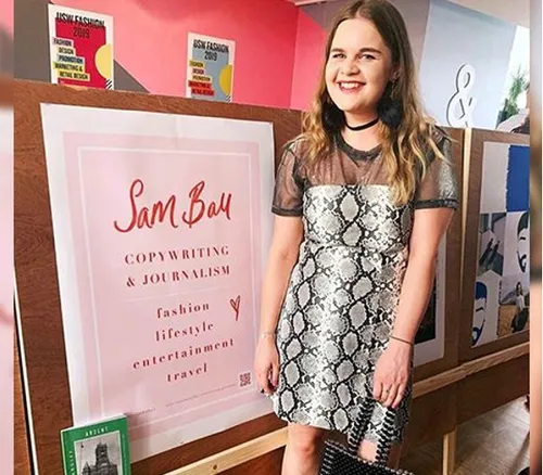 Fashion graduate, Sam, stands in front of sign to her copywriting event