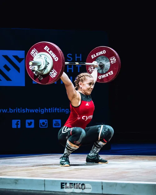Graduate, Chrisie, at a weight lifting competition, competing on stage.
