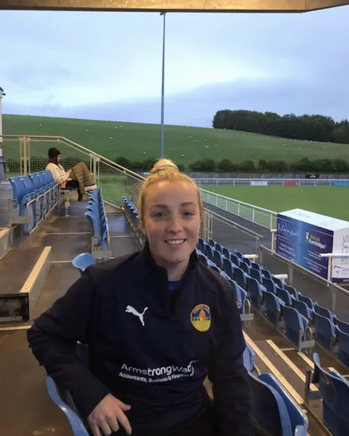 Georgia Smethurst, USW Alum, sitting in the stands of a football stadium.