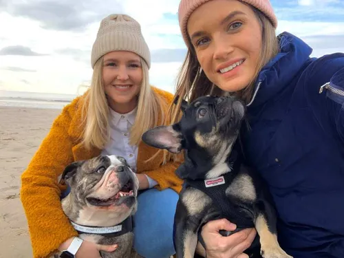 Lois and Charlotte pose for a selfie on the beach with their two dogs