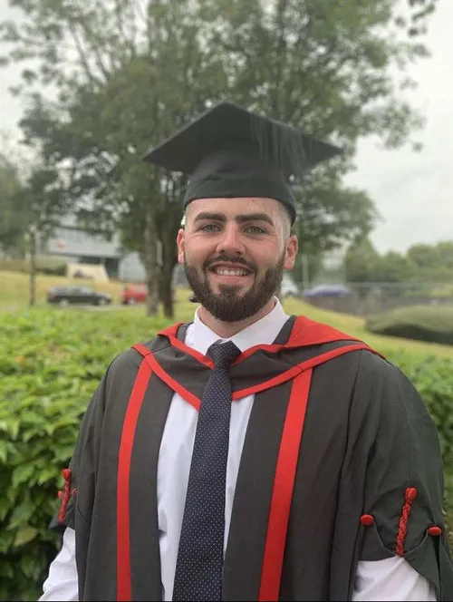 Graduate, Matthew Jones, smiling at the camera, wearing a graduation cap and gown.