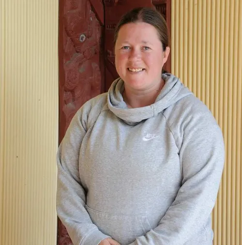 Graduate, Natalie Lawrence, is wearing a grey hoodie and smiling at the camera.