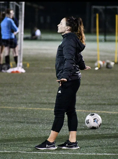 Graduate, Nicole Evans, coaching football players on a football pitch.