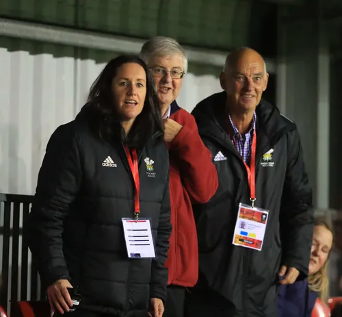 Graduate, Ria Burrage-Male, stood wearing a Hockey Wales branded coat with two colleagues.