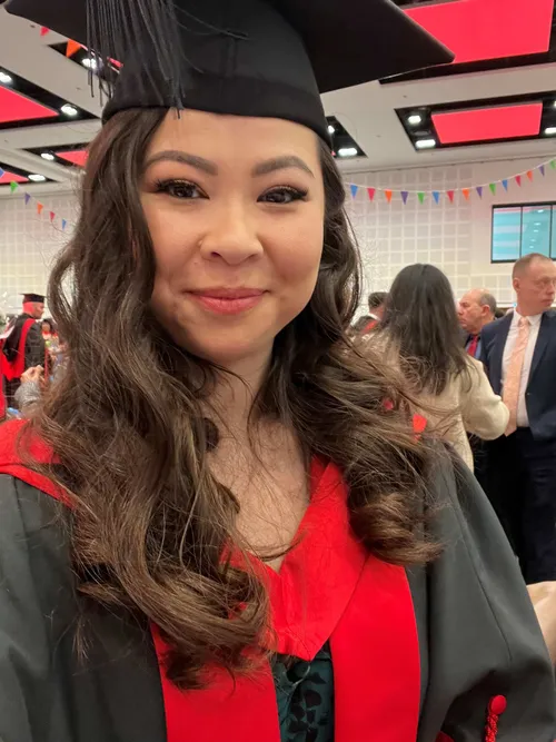 Precious O’Driscoll smiles at the camera while taking a selfie in a graduation cap and robes at a graduation ceremony