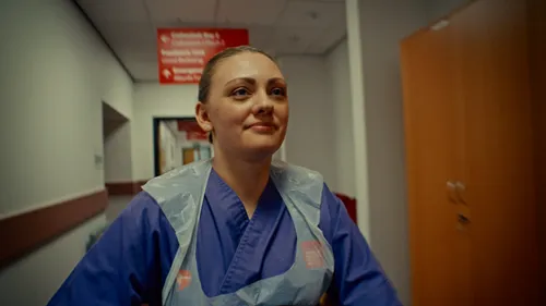 Close up shot of a nursing student wearing blue scrubs and an apron in the clinical simulation centre