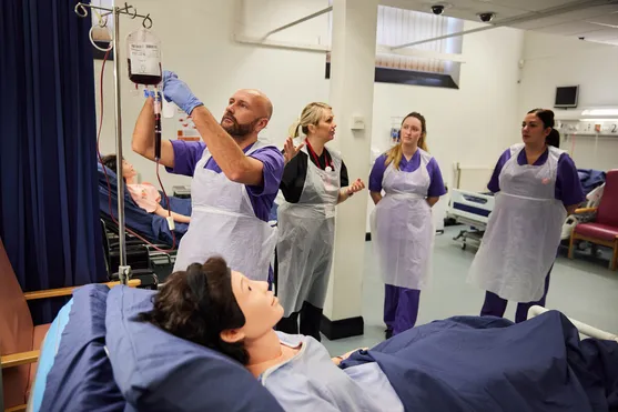 Nursing lecturer with students in a ward setting.