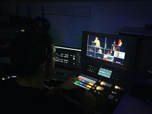 A student in a dark room working the lighting and sound for an event