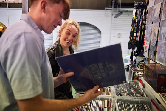 A student smiles as their friend shows them a record they've found at a shop in Pontypridd Market.