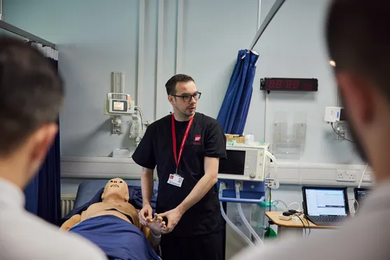 Lecturer, Jonathon Duffin using a dummy in the clinical simulation centre during a practical session with students observing