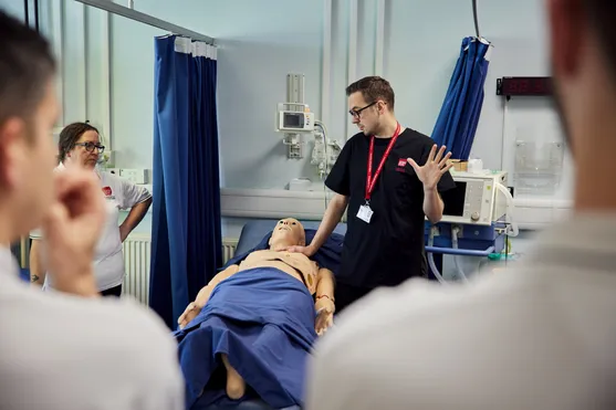 Lecturer, Jonathon Duffin using a dummy in the clinical simulation centre during a practical session with students observing