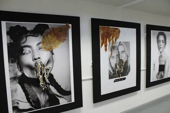 Famed pieces of student art consisting of black and white portraits of women, gold paint and added textured pieces of paper against a white wall
