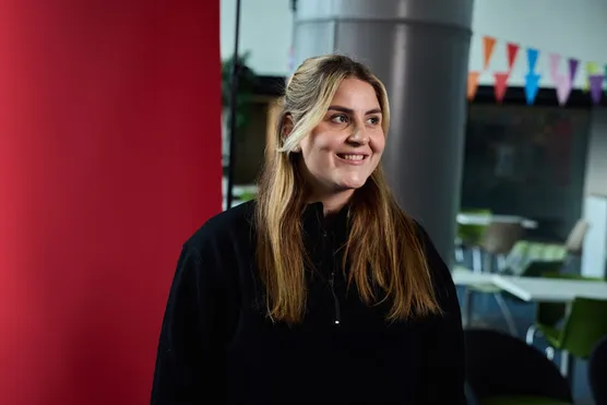 Student, Kaitlin, is smiling with a classroom in the background and looking slightly off camera.