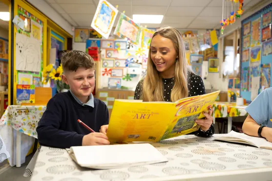 Primary teaching student Libby White reads a book to a primary school pupil in a classroom at Risca Primary School