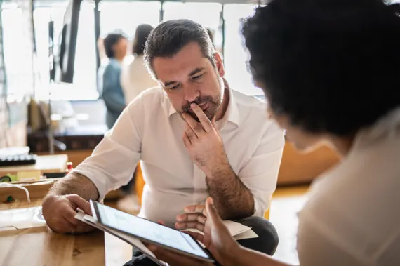 A staff mentor looking at a tablet that his colleague is holding