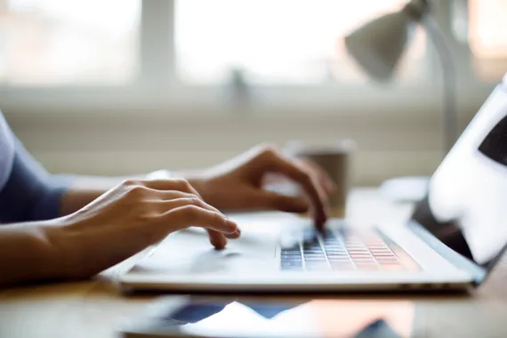 Hands of an unrecognisable person typing on a laptop