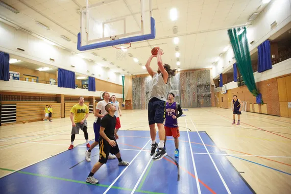 A group of students playing basketball with one of them scoring a point