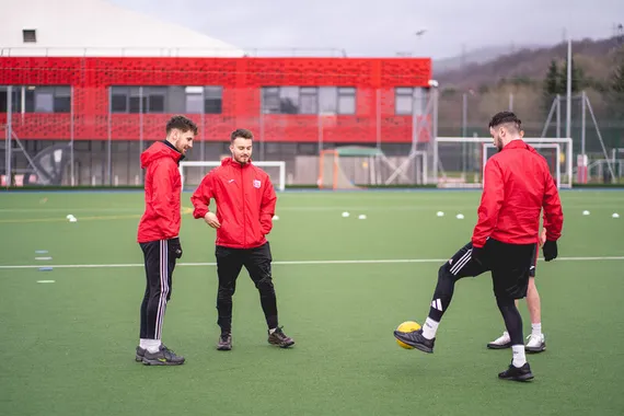 USW Sport students kicking a football on the outdoor pitch.