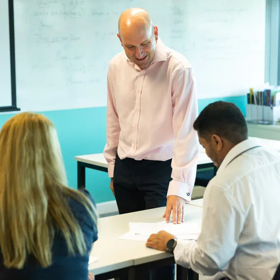 A lecturer and two posgraduate students engaged in conversation during a lecture at Newport campus