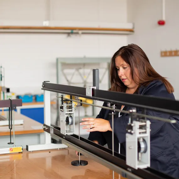 A mature student wearing a navy boiler suit uses a piece of equipment in a civil engineering workshop at USW Treforest