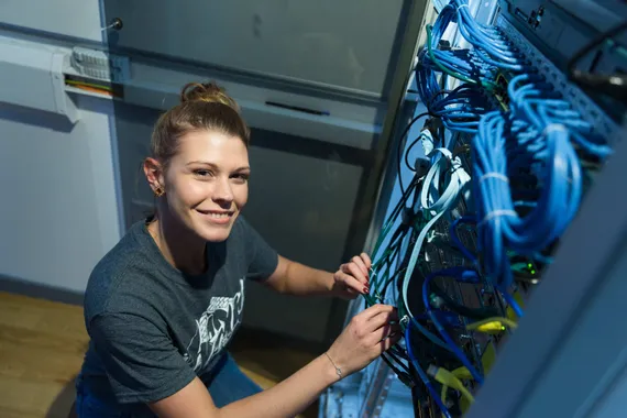 Nia Harris working on a computer wiring smiling to camera