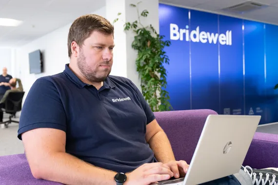 Student on placement working on laptop in front of bridewell logo