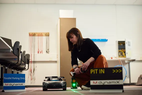 A automotive engineering student knelt down next to a model car