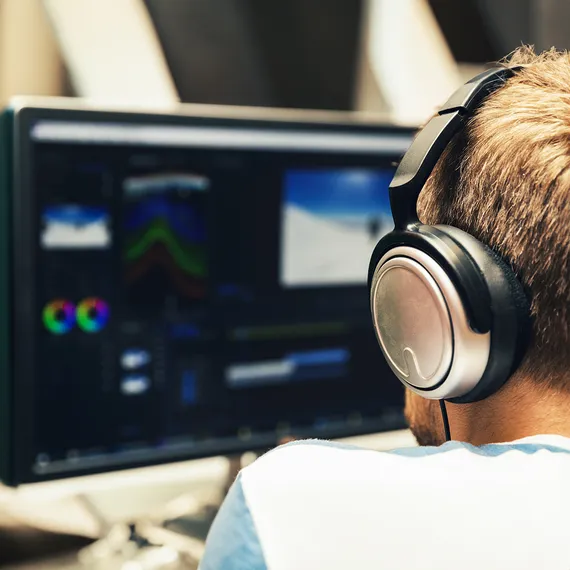 Student with headphones editing footage on a computer