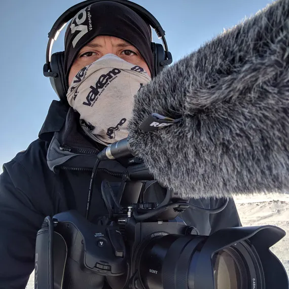 sam padget, USW Alumni, wrapped up scarf and hat with filming sound equipment