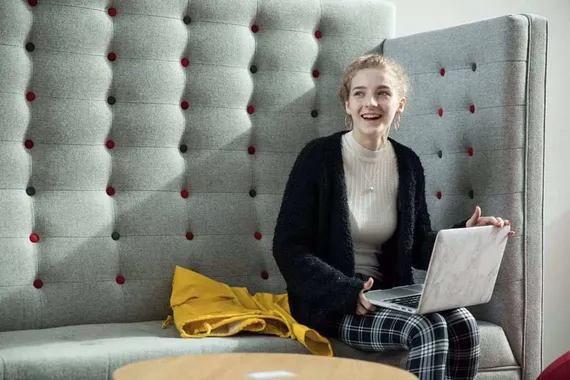 A student sat in a study booth with a laptop on their lap.