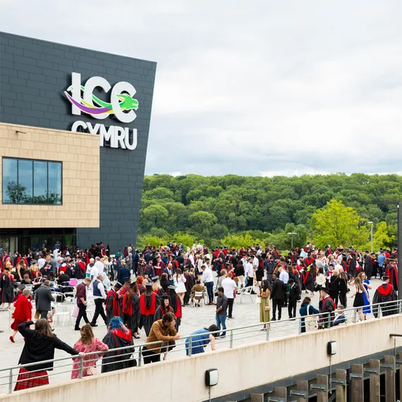 Students dressed in graduation robes and caps with their loved ones outside Newport's ICC