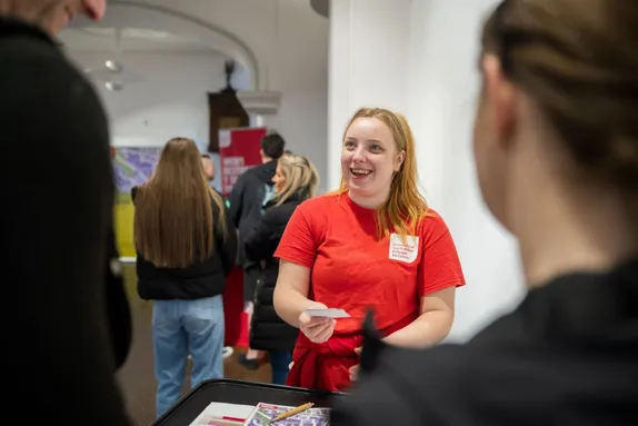 A smiling student ambassador greeting people at a USW Open Day.