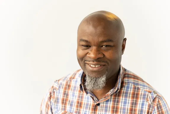 A close up of Dr Edward Oloidi smiling at the camera in front of a white backdrop