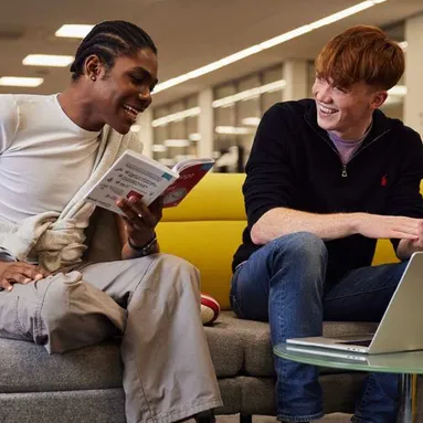 Two students laughing and studying in the library