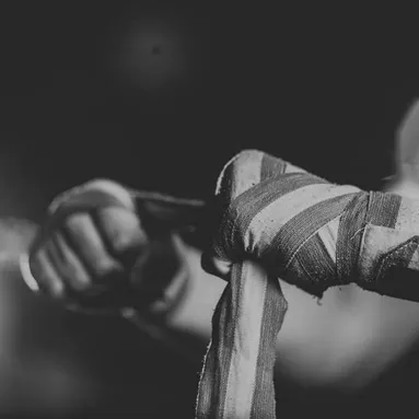 A pair of hands with boxing tape being wrapped around them, with a black and white overlay