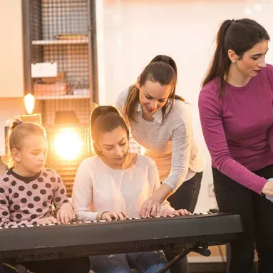 Dau athro cerdd yn arwain dau fyfyriwr i ganu'r piano
