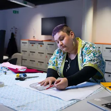 Amber Jones in a design studio measuring fabric with a rules and pencil