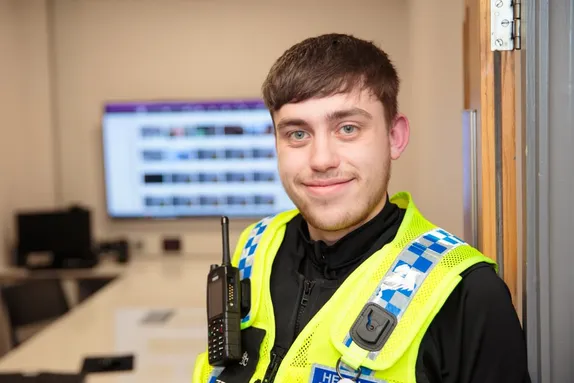A policing student in uniform wearing a hi-vis vest with radio attached.