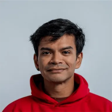 Person with short dark hair, wearing a red hoodie, looking at the camera with a smile.