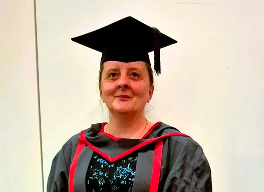 Beverley wearing red and black graduation gown and cap