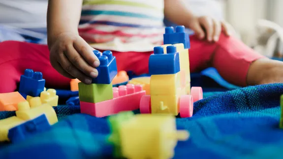 A toddler in soft focus putting together colourful building blocks in a childcare settting