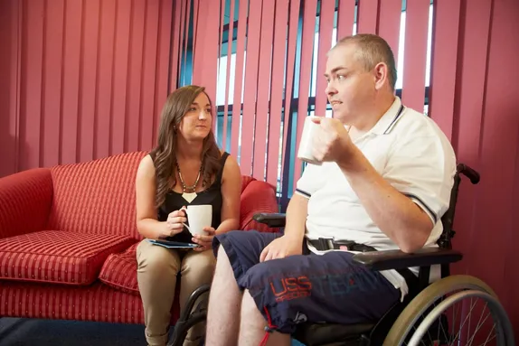 A learning disability nursing student has a cup of tea with a client.